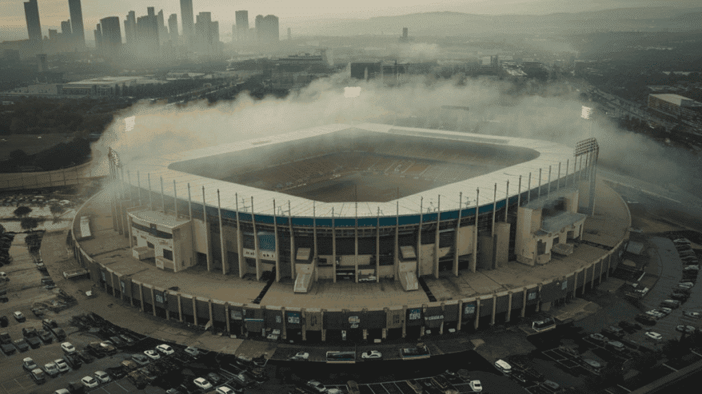 Aerial view of a packed sports stadium surrounded by urban development and smog.