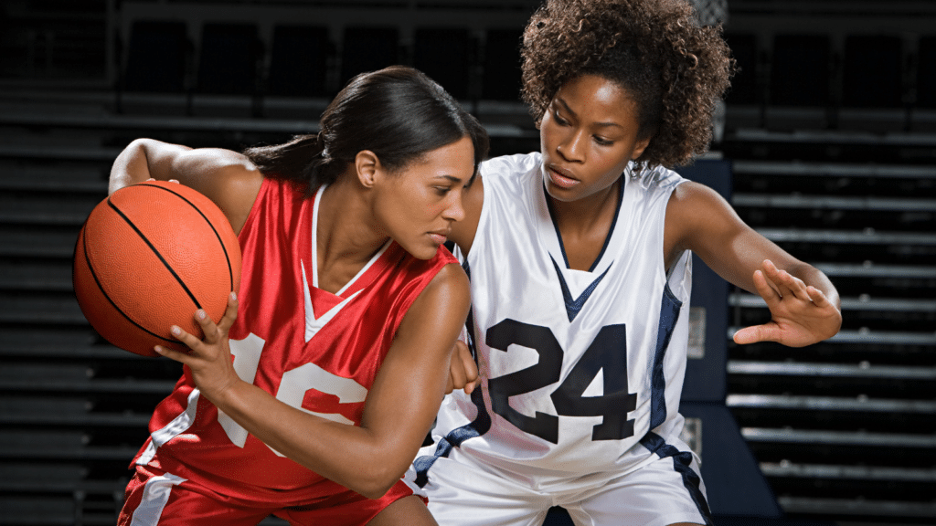 Two female basketball players in action during a game, showcasing athleticism and competition in women’s basketball.